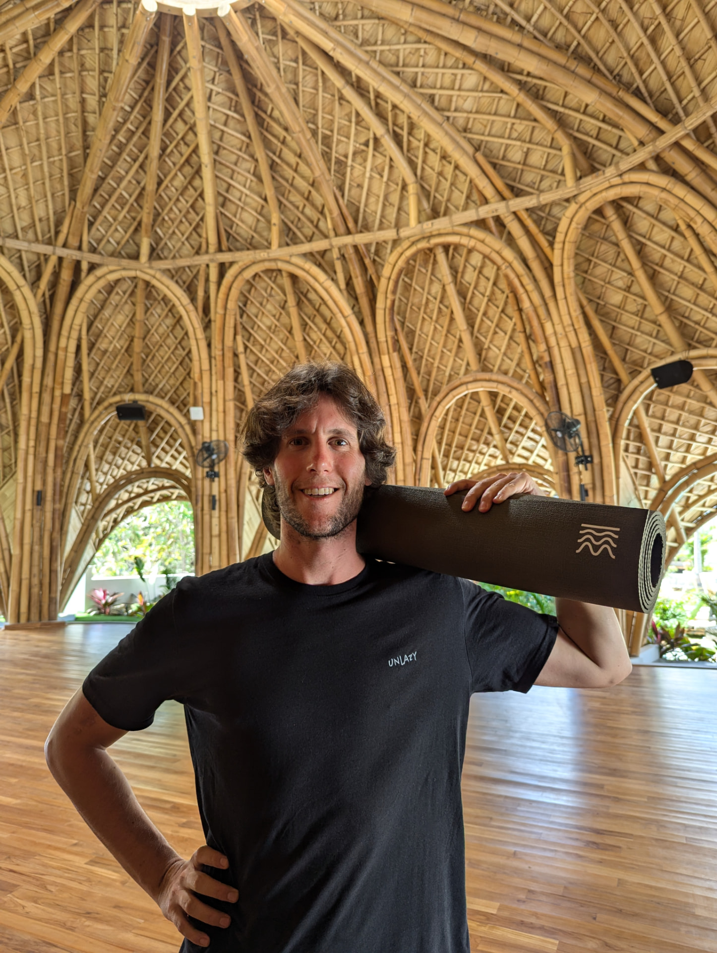Sean carrying a mat into a bamboo movement studio